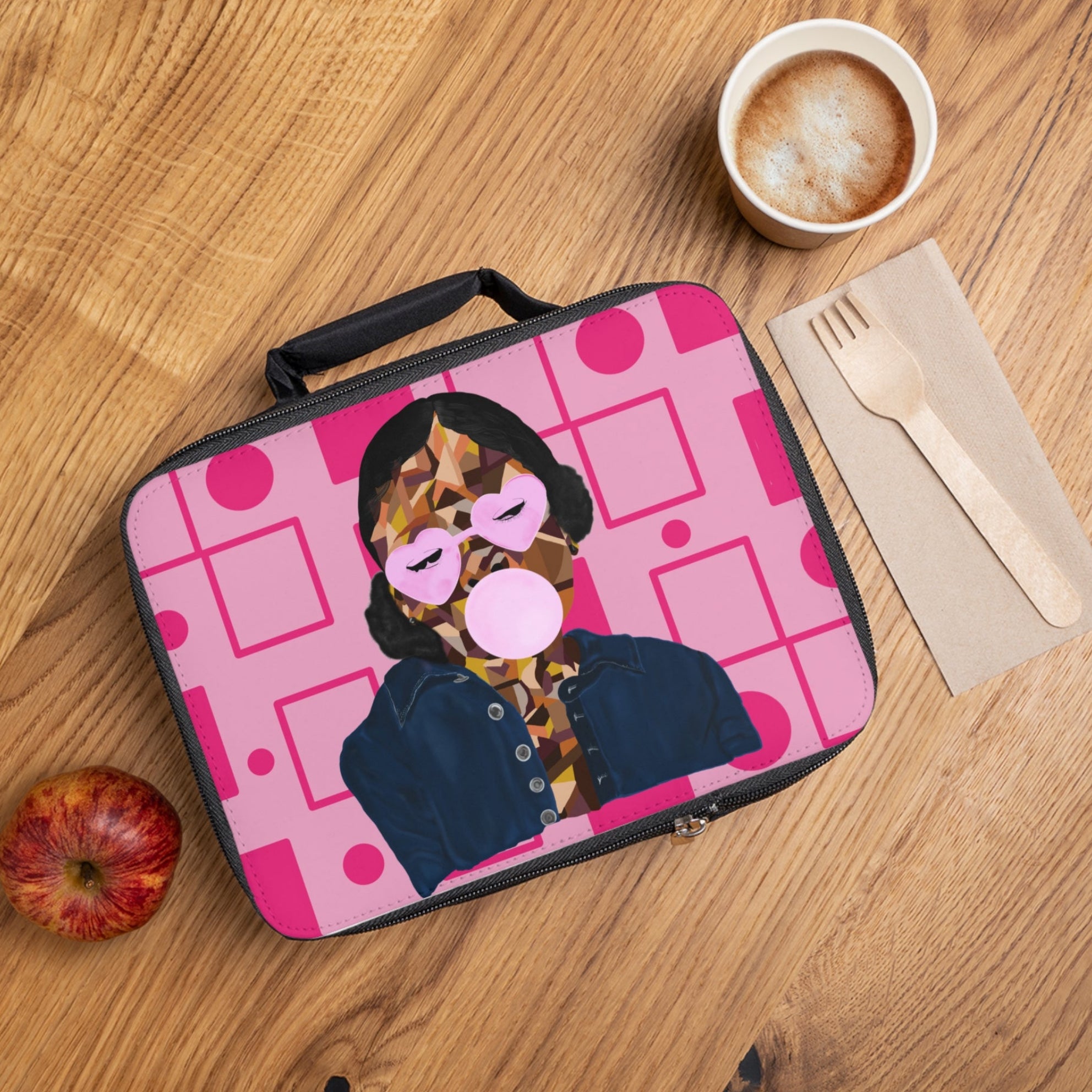 Lunch bag with a design of a person blowing a bubble gum bubble on a wooden table with an apple and coffee.